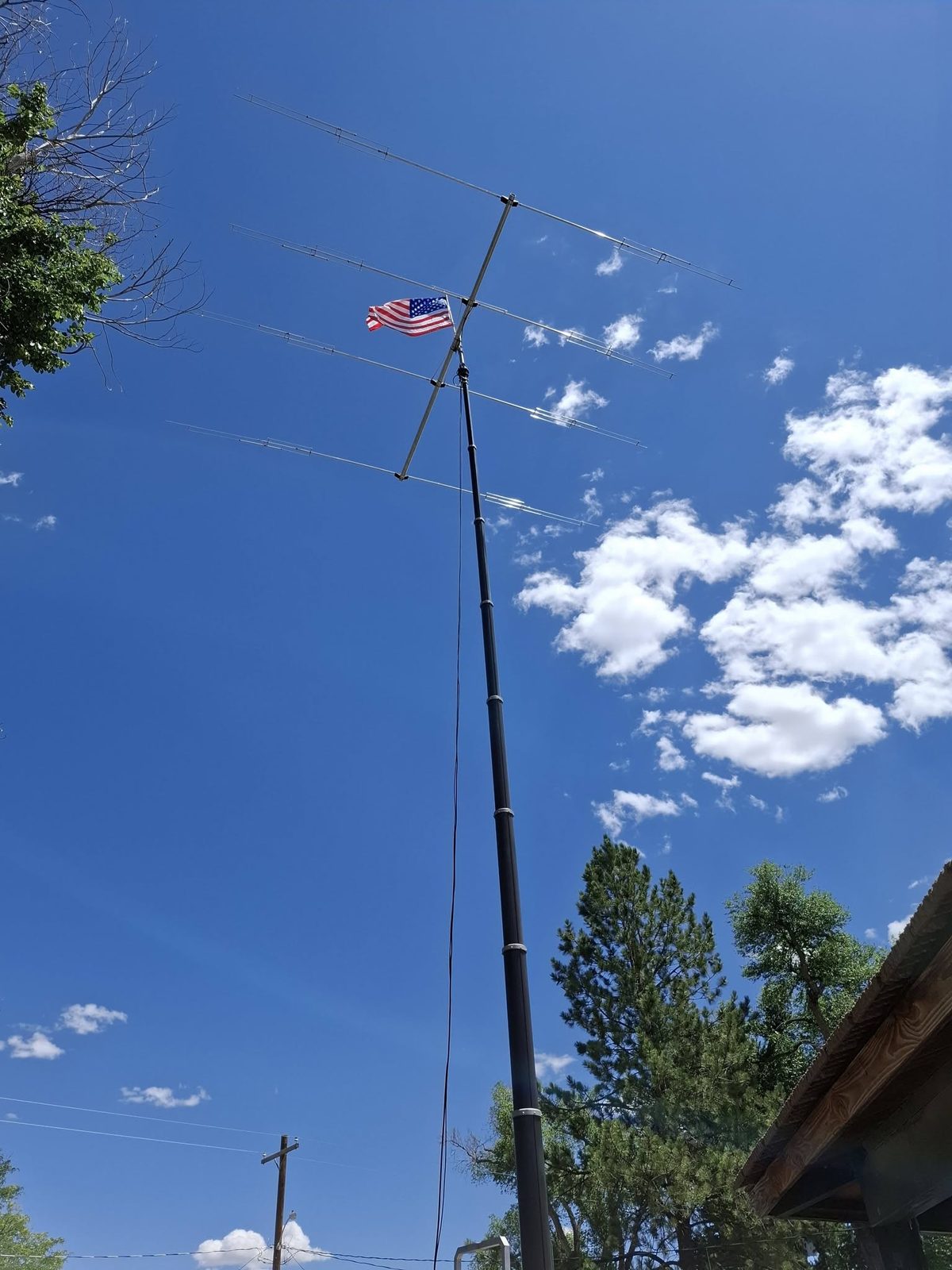 Portable mast, antennas and American flag against a blue Colorado sky.