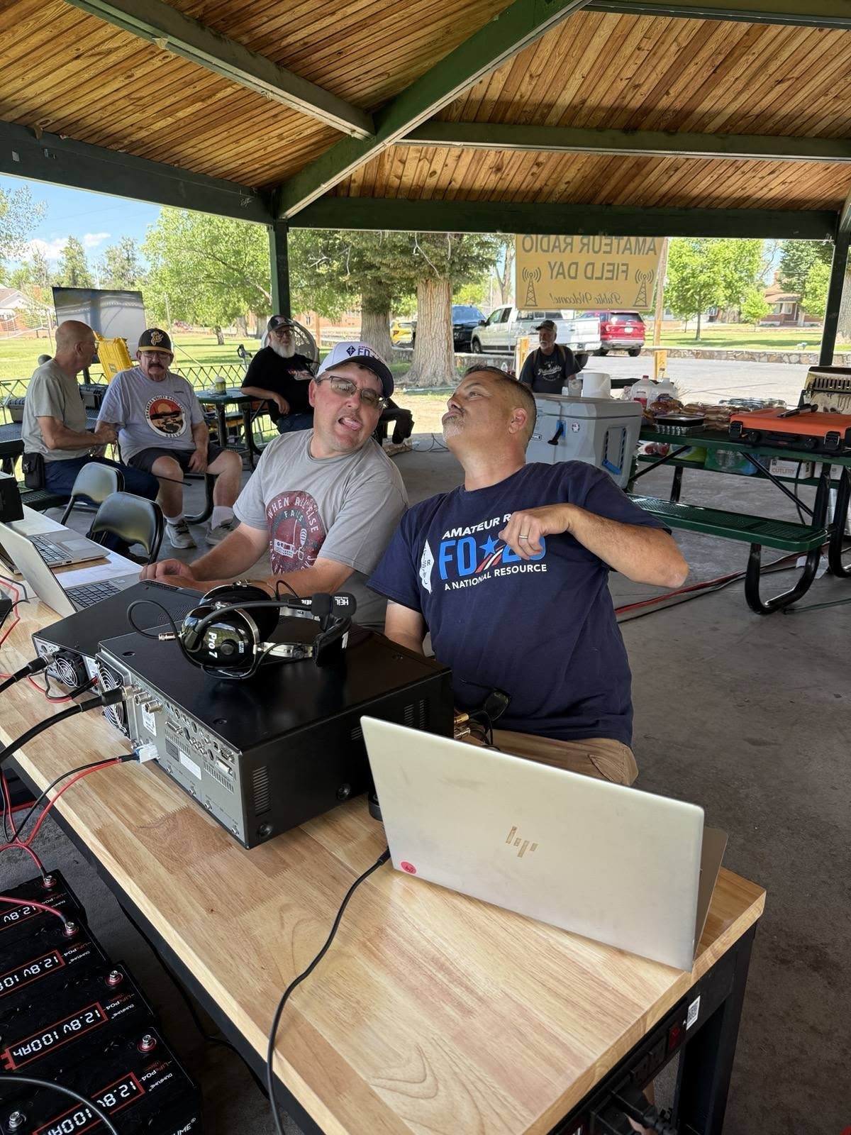 Two members at a station table with a transceiver and logging laptop.